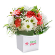 This bright and spirited bouquet, designed in New Addington's welcoming community, is presented upright in a neatly squared white gift bag, a vision of freshness and joy. The arrangement spills over with lush peach and coral carnations-each flower's ruffled petals layered for softness, the hues glowing like a friendly sunrise over the rooftops near Central Parade. Interspersed are pure white daisies, their dainty faces and golden-lime centers reminiscent of wildflowers seen on a stroll through nearby parks, bringing a sense of light-hearted celebration. Delicate sprigs of baby's breath drift between the larger blooms, adding a whisper of elegance and innocence, while generous satin-green leaves cross beneath, providing both structure and vibrancy. Peeking from the left, hints of purple from gently closed buds inject depth and a touch of mystery-a promise of more beauty yet to emerge. The bouquet forms a gentle, full curve, the careful handiwork plain in every detail. Finished with glossy ribbon handles, the bag sits against a clean white backdrop, ready to be lifted and delivered to a doorstep on Calley Down Crescent, or presented at a birthday tea just off Goldcrest Way. This arrangement radiates the joy and connection that comes from thoughtful gifting-perfect for marking major occasions, surprising someone special, or simply brightening a day in New Addington with a flourish of exquisite, locally crafted blooms.
